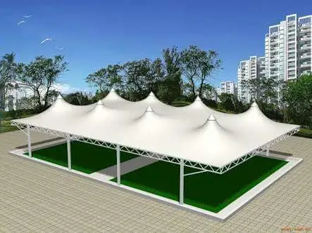 White Multi peak Tensile Canopy over Green Artificial Turf Sections in a Park with Trees and Tall Buildings in the Background