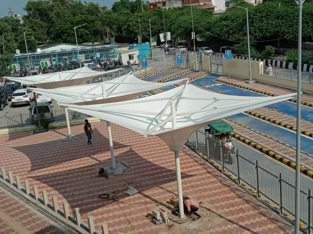 Wide View of White Tensile Shade Sails over a Tiled Plaza Construction Tools Lie on the Ground As a Person Walks Nearby